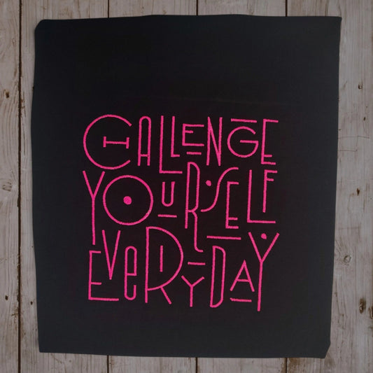 Challenge Yourself Everyday embroidered text on black t-shirt in pink thread