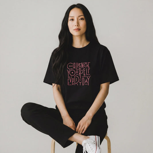 Woman wearing black oversized t-shirt with pink Challenge Yourself Everyday embroidery
