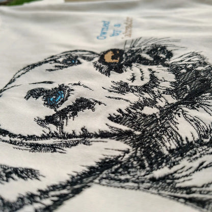 Angled detail shot of Labrador embroidery and ice blue Owned by a Labrador text on cream tee — Embroidist