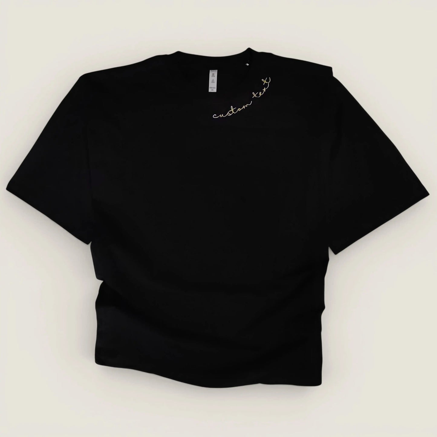 Back neckline close-up — custom name machine embroidered in brush script on black tee