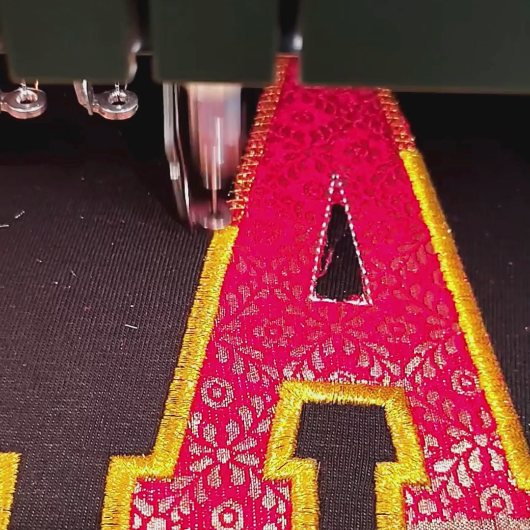 Zari fabric letter being embroidered on black t-shirt – custom embroidery process at Embroidist