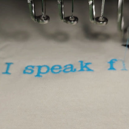 German Shepherd embroidery t-shirt — machine embroidered GSD illustration with ice blue "I speak fluent German Shepherd" text on cream oversized tee, custom made in India by Embroidist