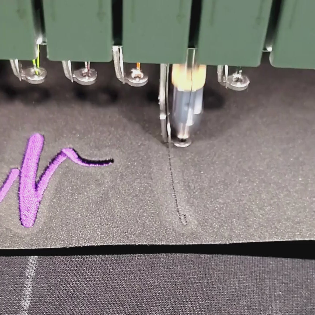 Embroidery machine stitching custom 3D puff design on black t-shirt fabric
