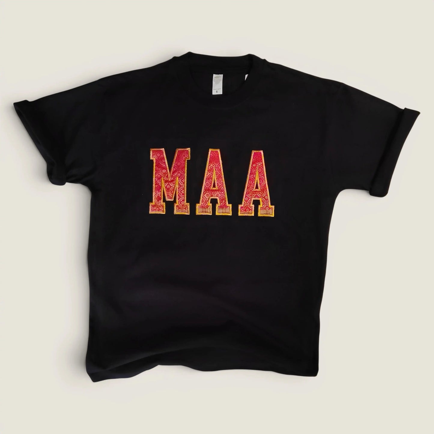 Flat lay of custom Zari embroidery t-shirt with MAA in pink and gold letters | Embroidist
