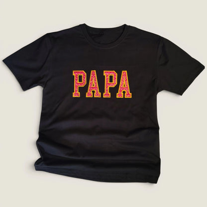Flat lay of custom Zari embroidery t-shirt with PAPA in pink and gold varsity letters | Embroidist