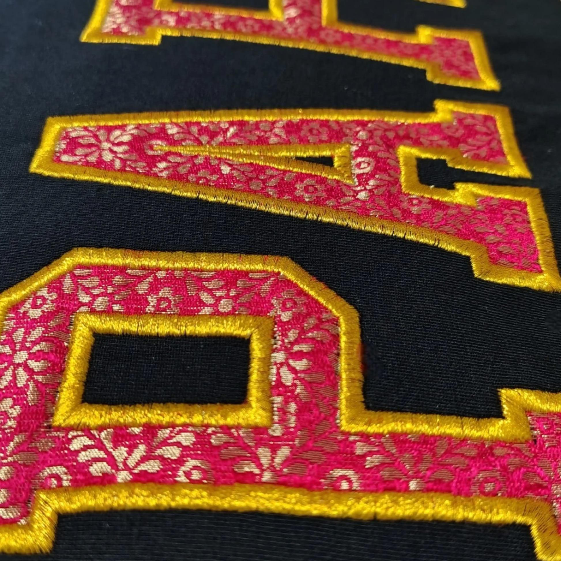 Close-up of Zari fabric varsity letter embroidery on black t-shirt – custom embroidery by Embroidist